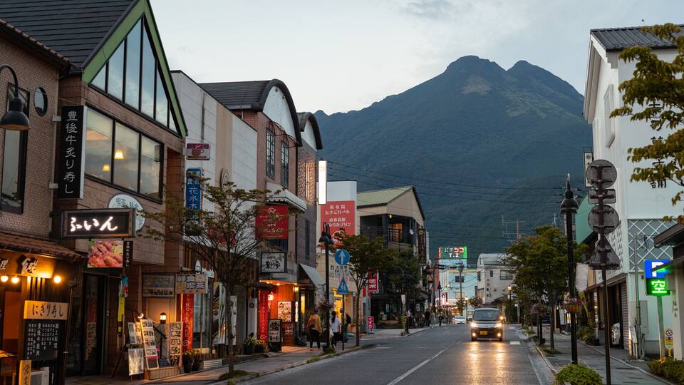 A street lined with shops and restaurants, with a mountain in the background.
