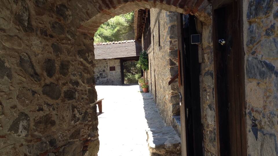 A narrow stone pathway leading through an old stone building with a wooden door and a small window.
