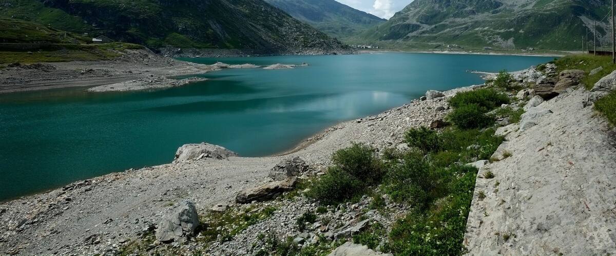 A mountain lake with rocky shores and surrounding green hills.