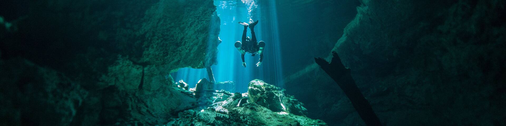A diver in a cave with stalactites and stalagmites.