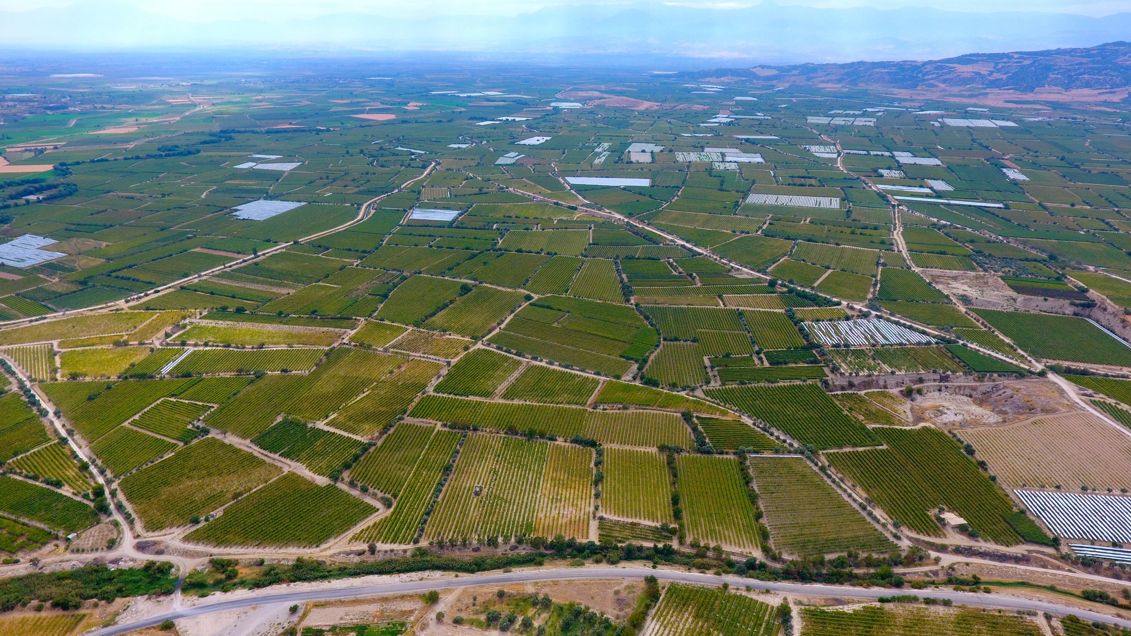 An aerial view of a large agricultural area with numerous fields, roads, and scattered buildings.