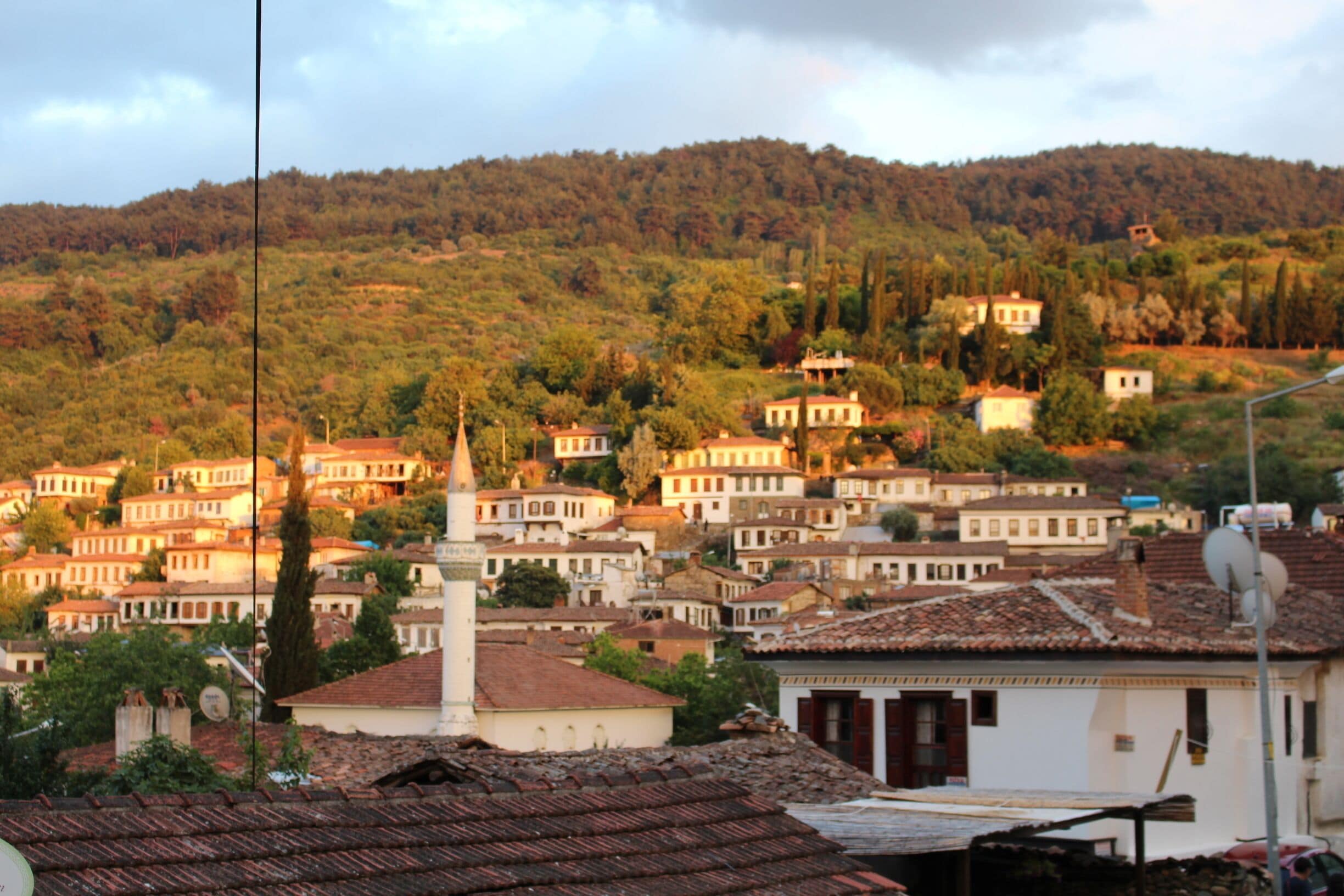 A hillside village with terracotta-roofed houses and a prominent church steeple.