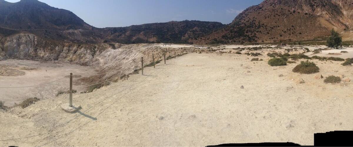A barren landscape with a large crater surrounded by mountains.