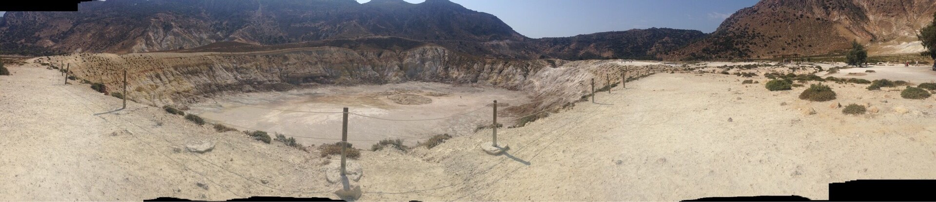 A barren landscape with a large crater surrounded by mountains.