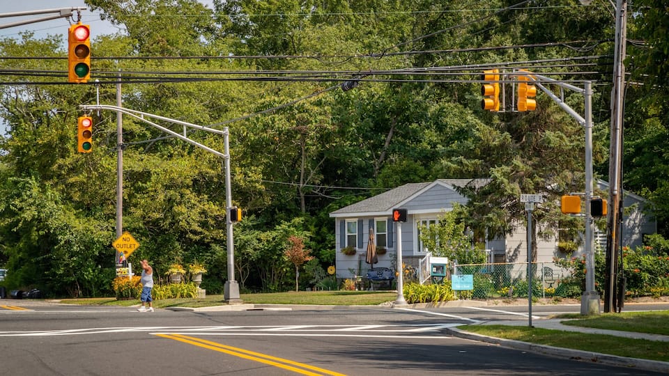 A traffic light intersection with a house in the background.