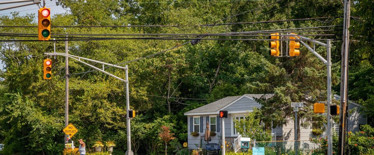 A traffic light intersection with a house in the background.