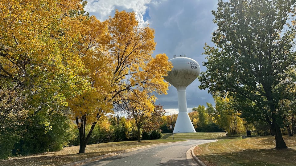 A park with a distinctive water tower labeled 'BROOKLYN PARK' amidst autumn foliage.