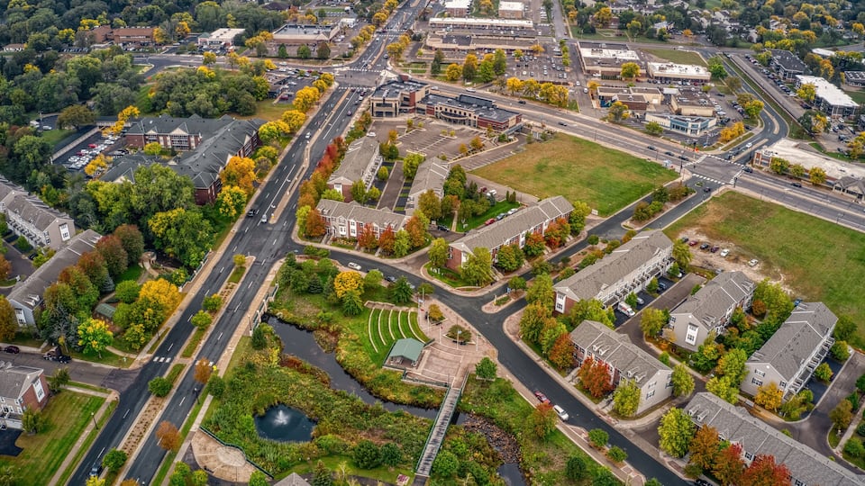 An aerial view of a suburban area with a mix of residential buildings, roads, and green spaces.