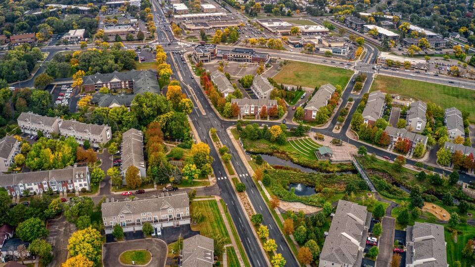 An aerial view of a suburban area with residential buildings, roads, and green spaces.