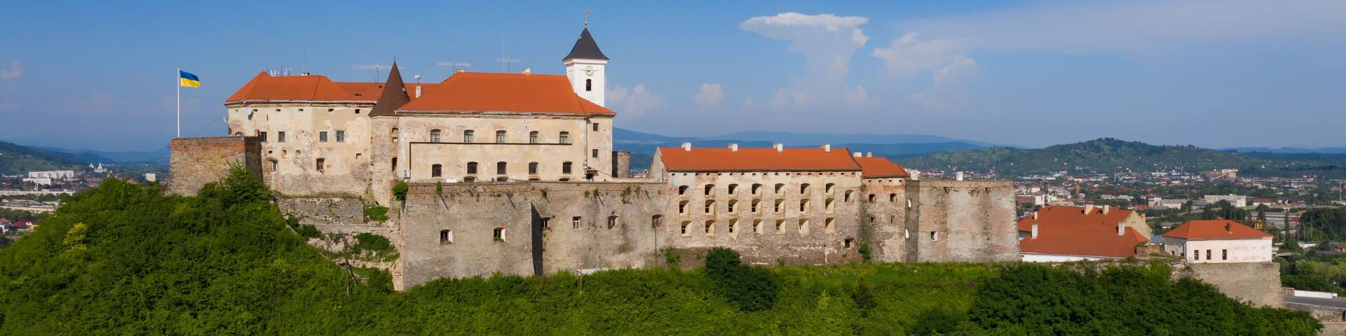 Picturesque view to the Palanok Castle with the red roofs under the blue sky in Mukachevo, Transcarpathian region in Ukraine. Horizontal outdoors shot.