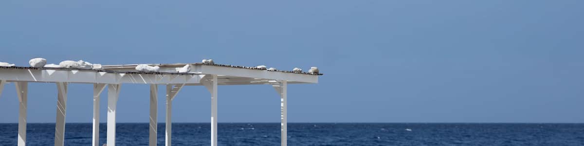 A white gazebo with a clear view of the ocean and a blue sky.