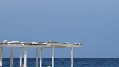 Un quiosco blanco con vista despejada al océano y un cielo azul.