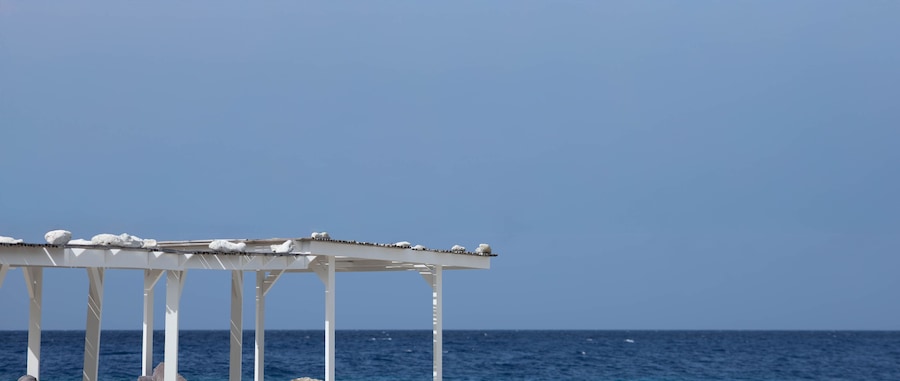 A white gazebo with a clear view of the ocean and a blue sky.