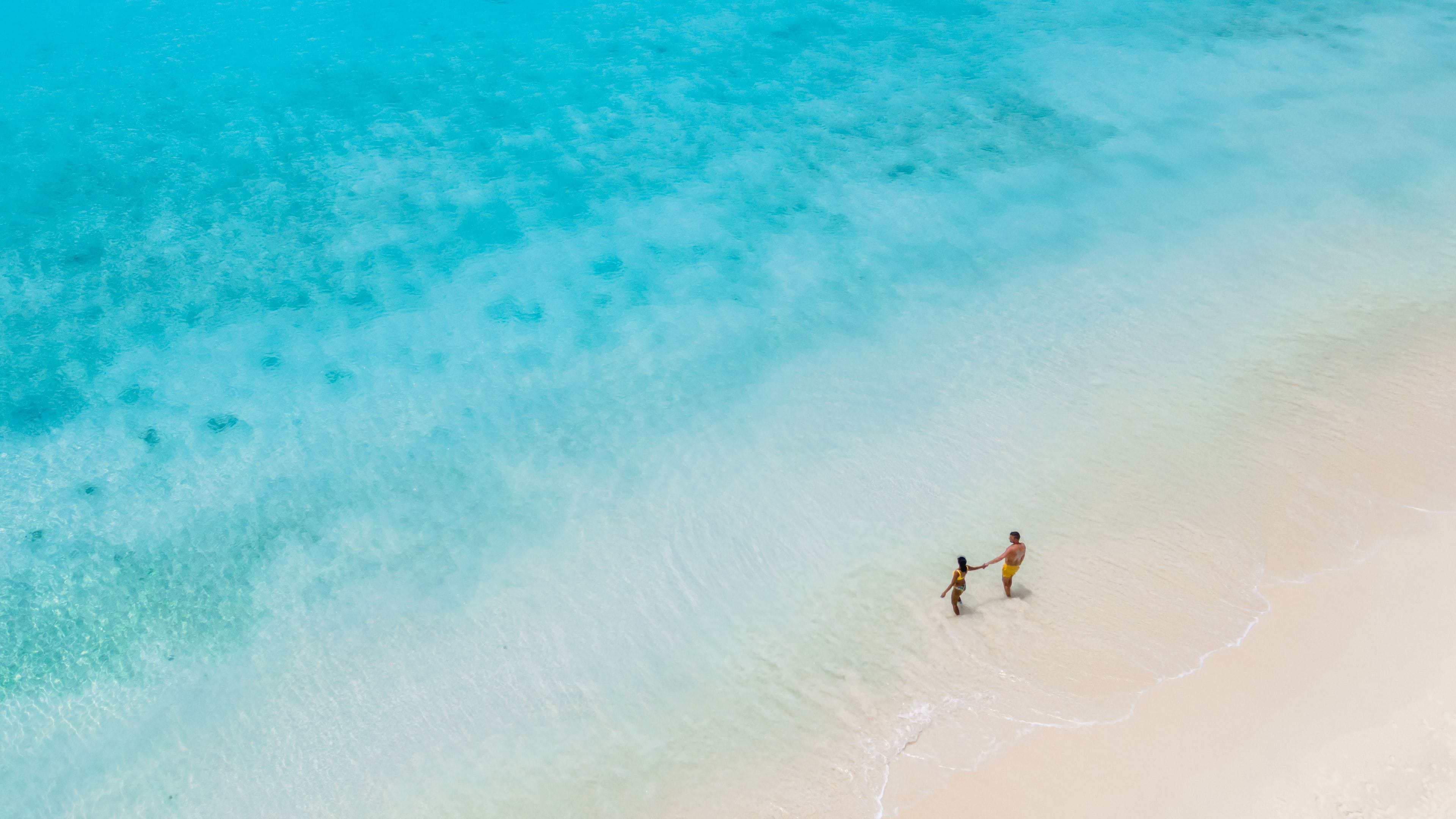 Een strand met helder turquoise water en een zandstrand.