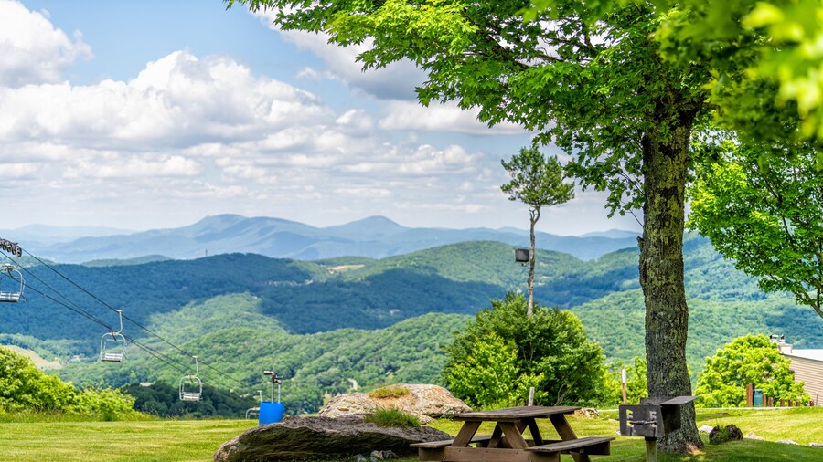 Sugar Mountain ski resort town park with idyllic picnic table bench under tree and view of ski chair slope and beautiful green North Carolina Blue Ridge Appalachia