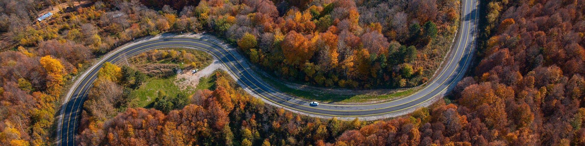 A winding road through a forest with autumn foliage.