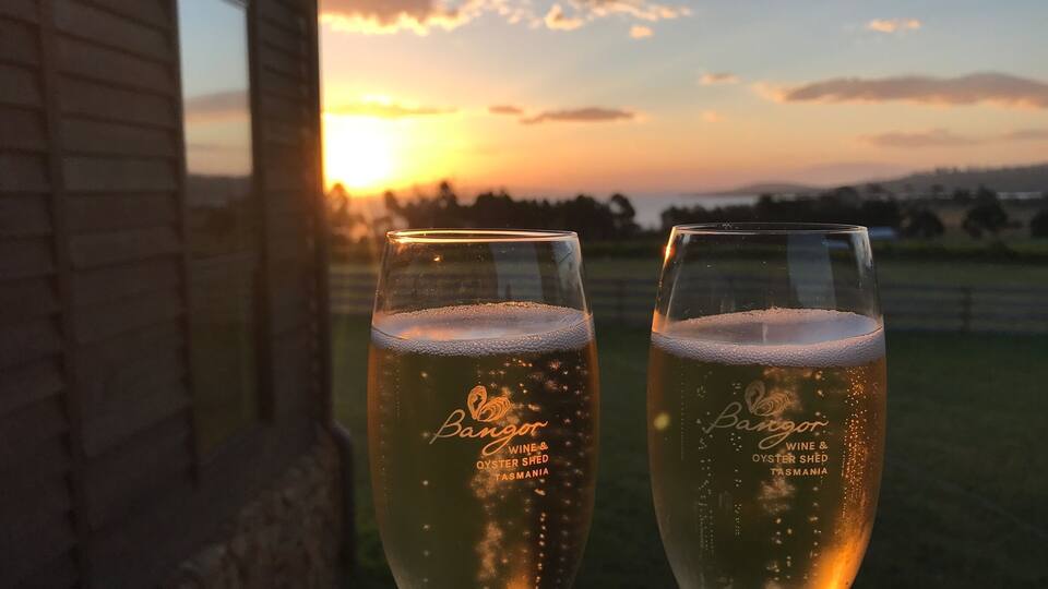 Two glasses of wine with a sunset in the background.