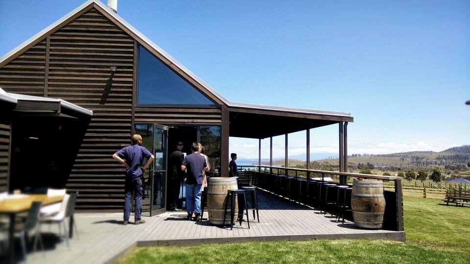 A modern building with a sloped roof and a covered outdoor seating area overlooking a scenic landscape.
