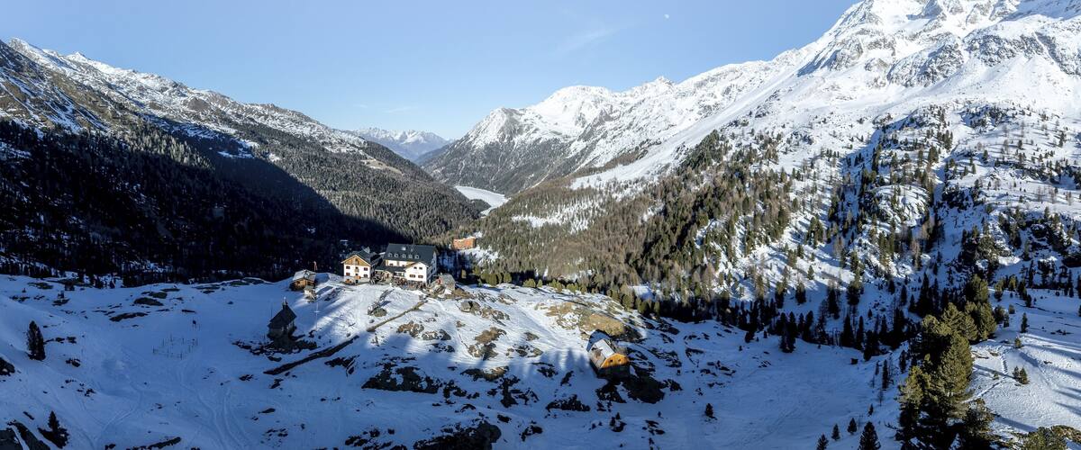 A snow-covered mountain landscape with a small village and a lake in the valley.
