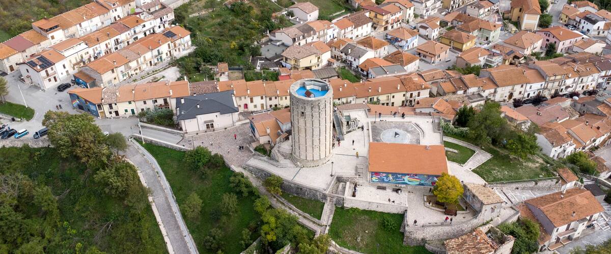 An aerial view of a historic town with a prominent tower, narrow streets, and traditional architecture.