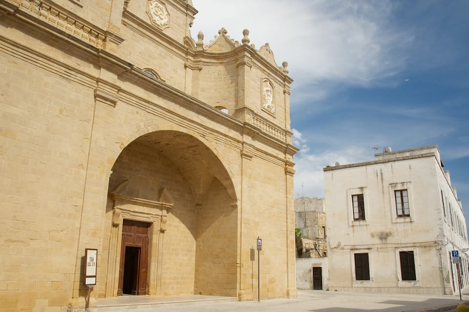 Un edificio histórico de piedra con una entrada arqueada y una torre del reloj.