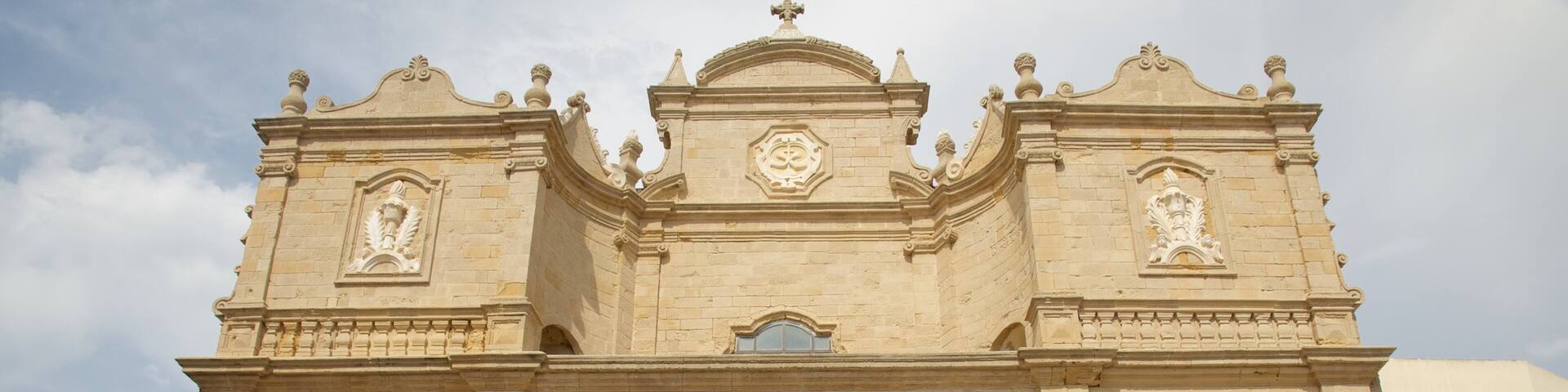 A historic stone building with ornate architectural details, including a large arched entrance and decorative elements above the door.
