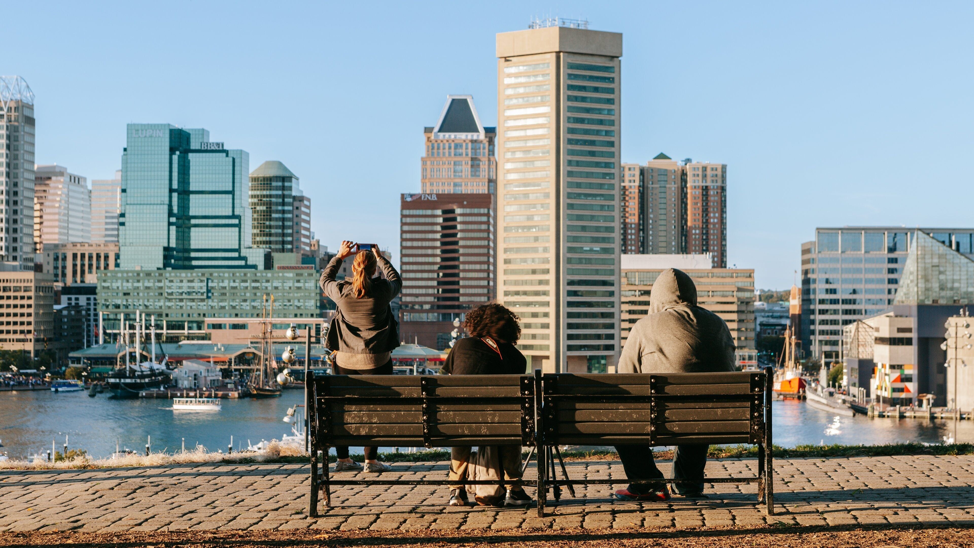 Federal Hill Park which includes a bay or harbor and a city as well as a small group of people