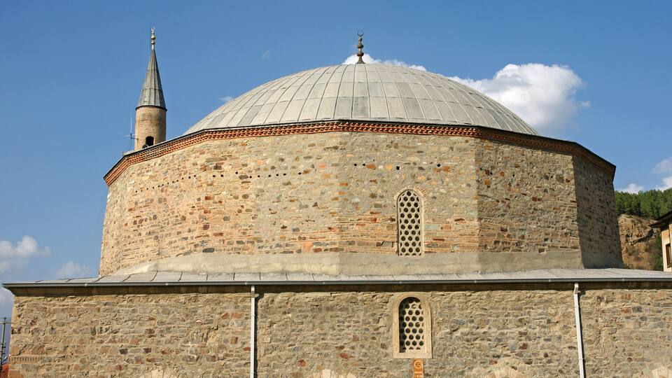 A historic stone building with a dome and a minaret.
