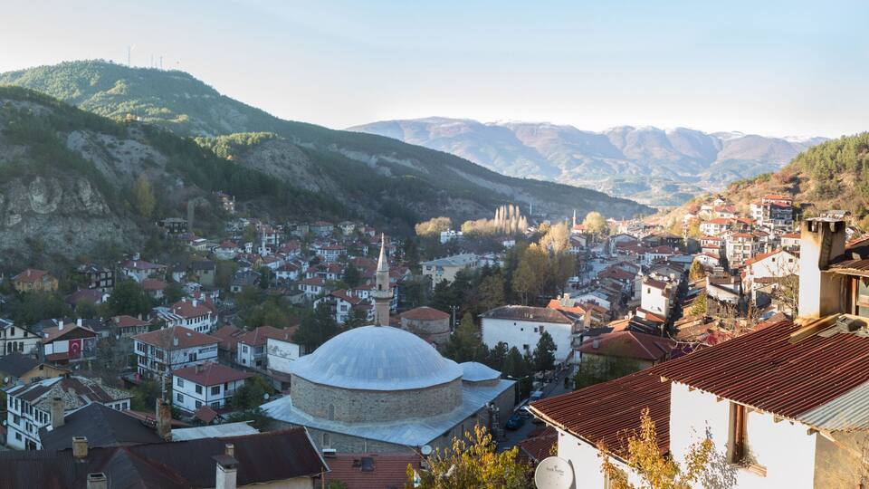 A mountainous town with a prominent mosque and a variety of residential buildings.