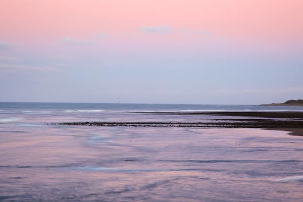 Fitzroy Beach welches beinhaltet Sonnenuntergang und Bucht oder Hafen