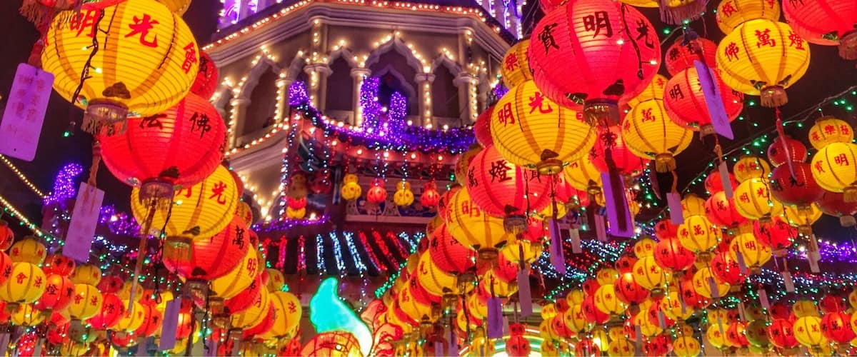 A brightly lit pagoda with traditional Chinese architecture, surrounded by numerous red and yellow lanterns.