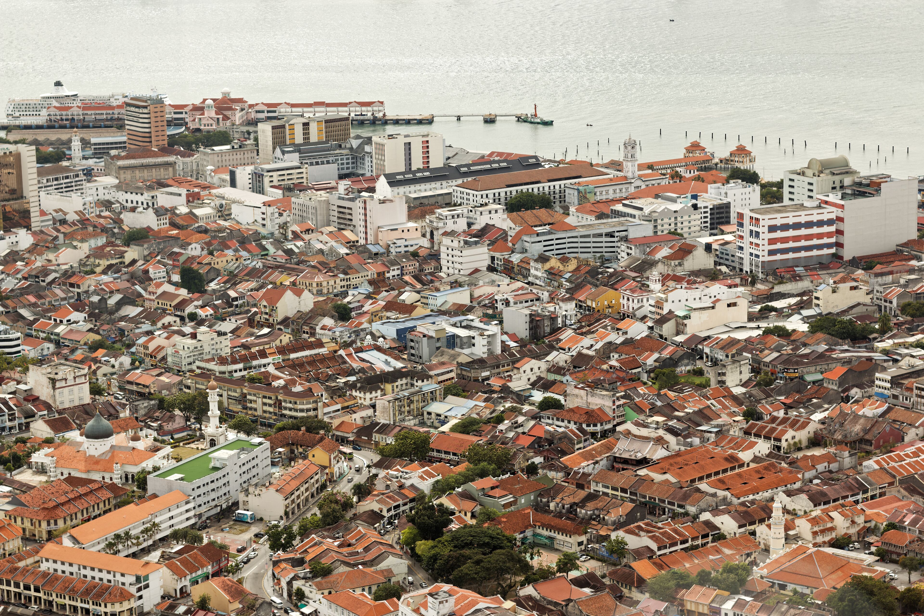 A coastal cityscape with dense urban architecture, including historic buildings and a prominent lighthouse.