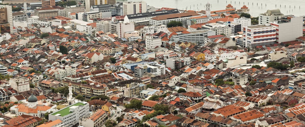 A coastal cityscape with dense urban architecture, including historic buildings and a prominent lighthouse.