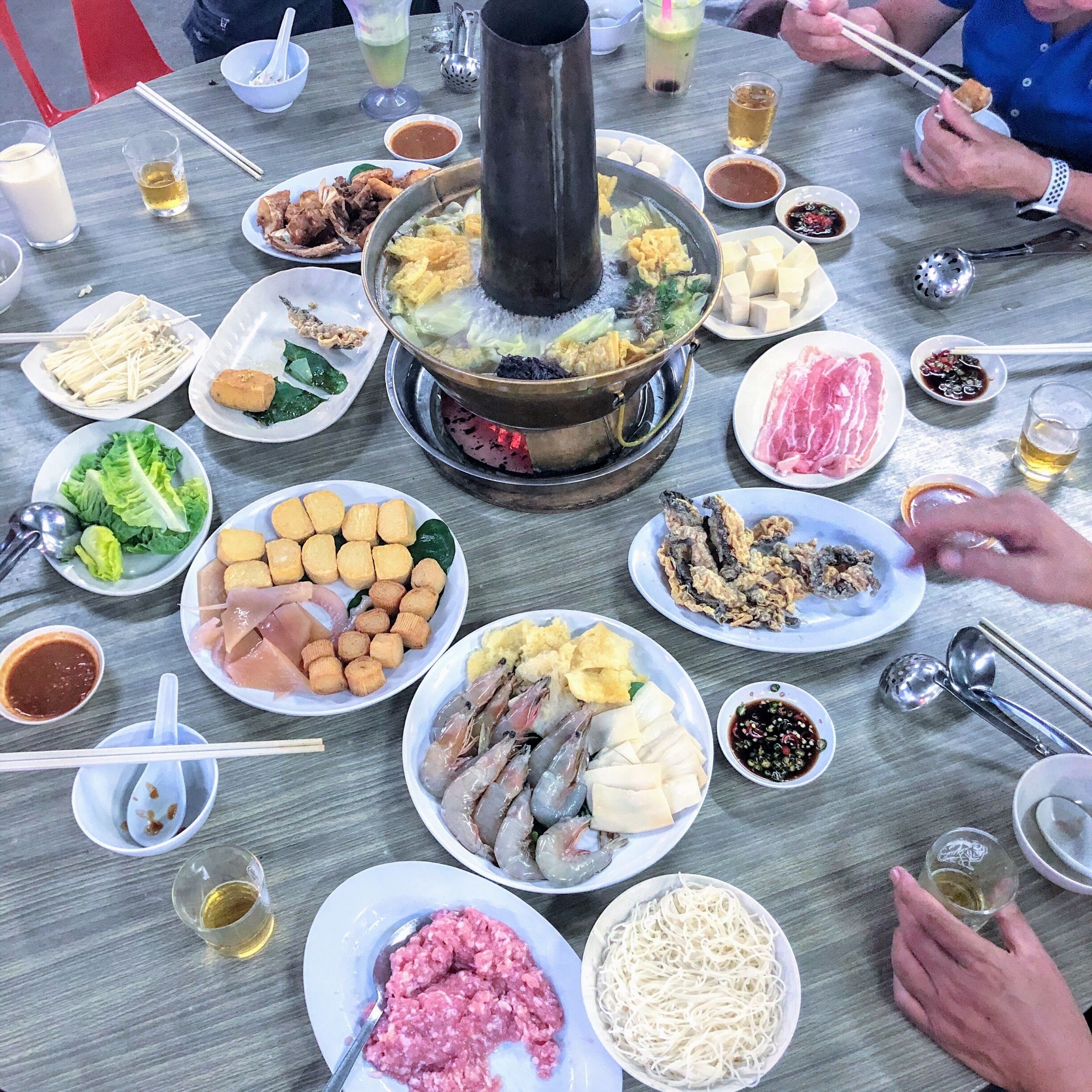 A table with various dishes, including seafood, vegetables, and a hot pot.