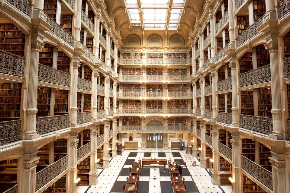 Una biblioteca imponente con arquitectura ornamentada, varios niveles de estanterías y un espacio central abierto con mesas.