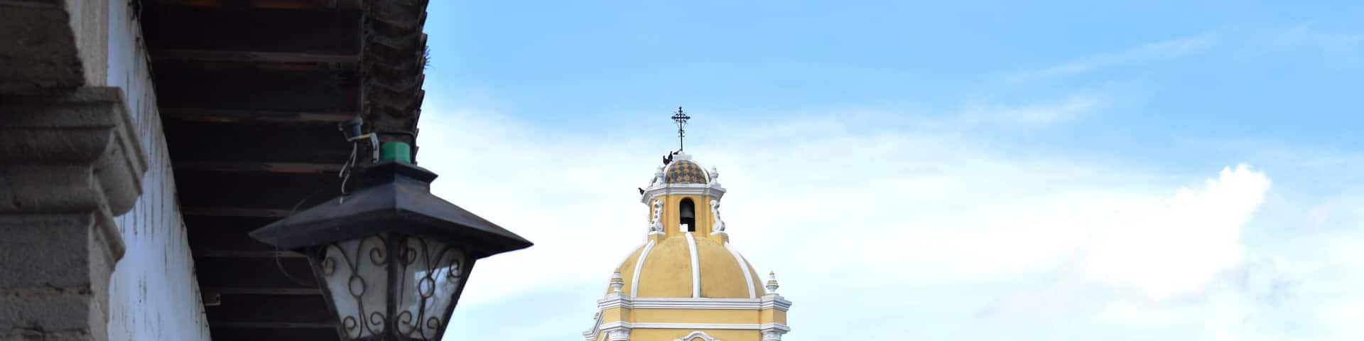 A yellow building with a clock tower and a dome.