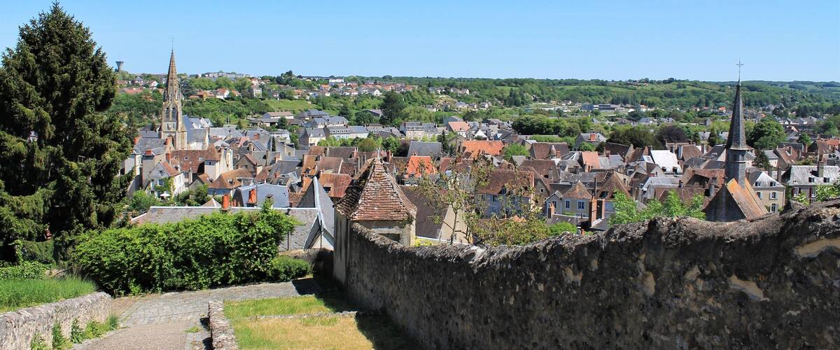 A historic town with a prominent church tower, cobblestone streets, and a stone wall.