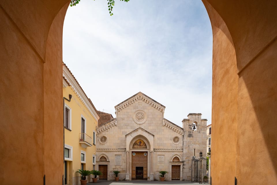 A historic building with a central dome and arched entrance, framed by a stone archway.