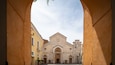 A historic building with a central dome and arched entrance, framed by a stone archway.