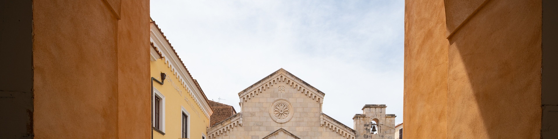 Um edifício histórico com cúpula central e entrada em arco, emoldurado por um arco de pedra.