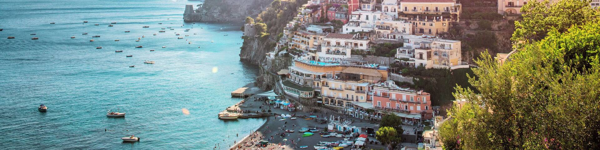A coastal town with colorful buildings on a hillside, boats on the water, and a clear sky.