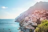 A coastal town with colorful buildings on a hillside, boats on the water, and a clear sky.
