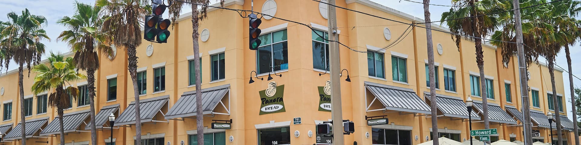 A yellow building with palm trees, a white truck, and a street sign.
