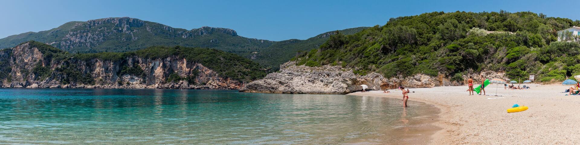 Panorama of beautiful Rovinia Beach with turquoise water and rocks during summer vacations, Corfu, Greece
