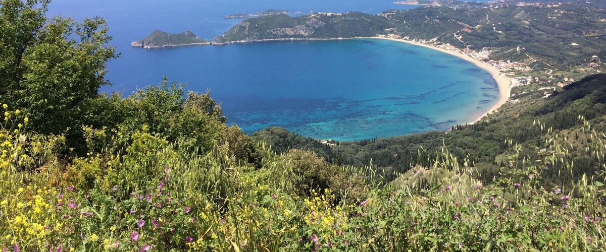 A coastal landscape with a bay, hills, and a clear sky.