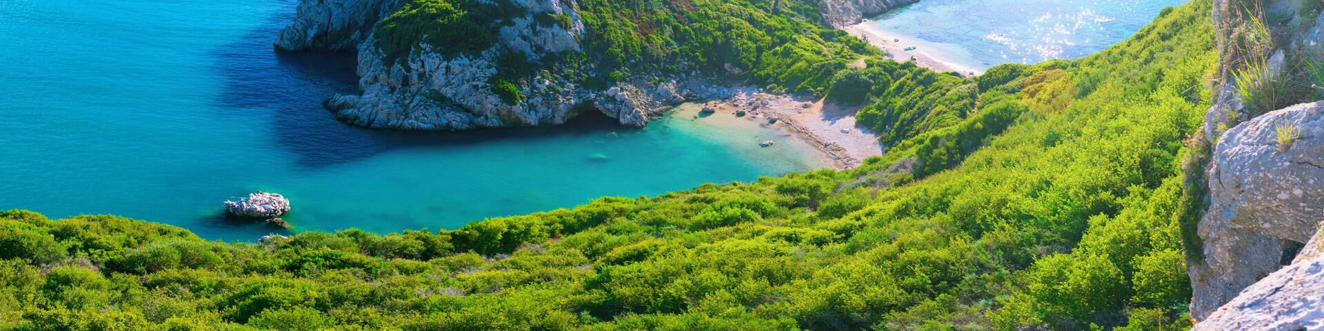 Beautiful summertime panoramic seascape. View of the cliff into the crystal clear azure sea bay and distant islands. Unique secluded beach. Agios Stefanos cape. Afionas. Corfu. Greece.