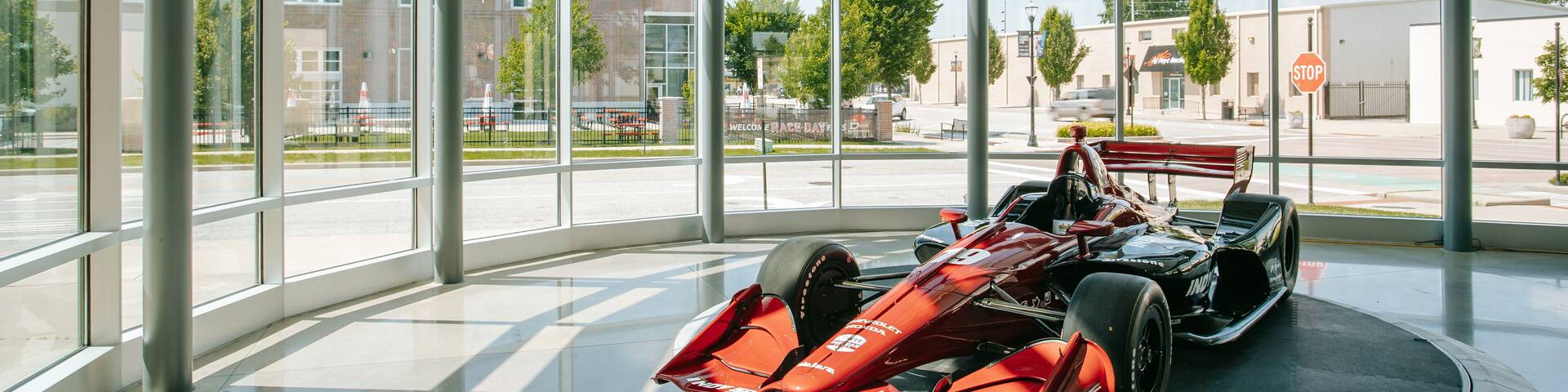 A red Formula 1 car in a glass-walled indoor exhibit.