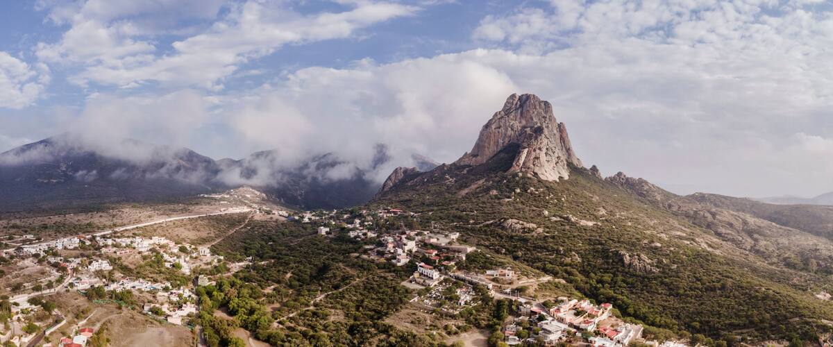 A mountain with a prominent peak, a town at its base, and surrounding hills.