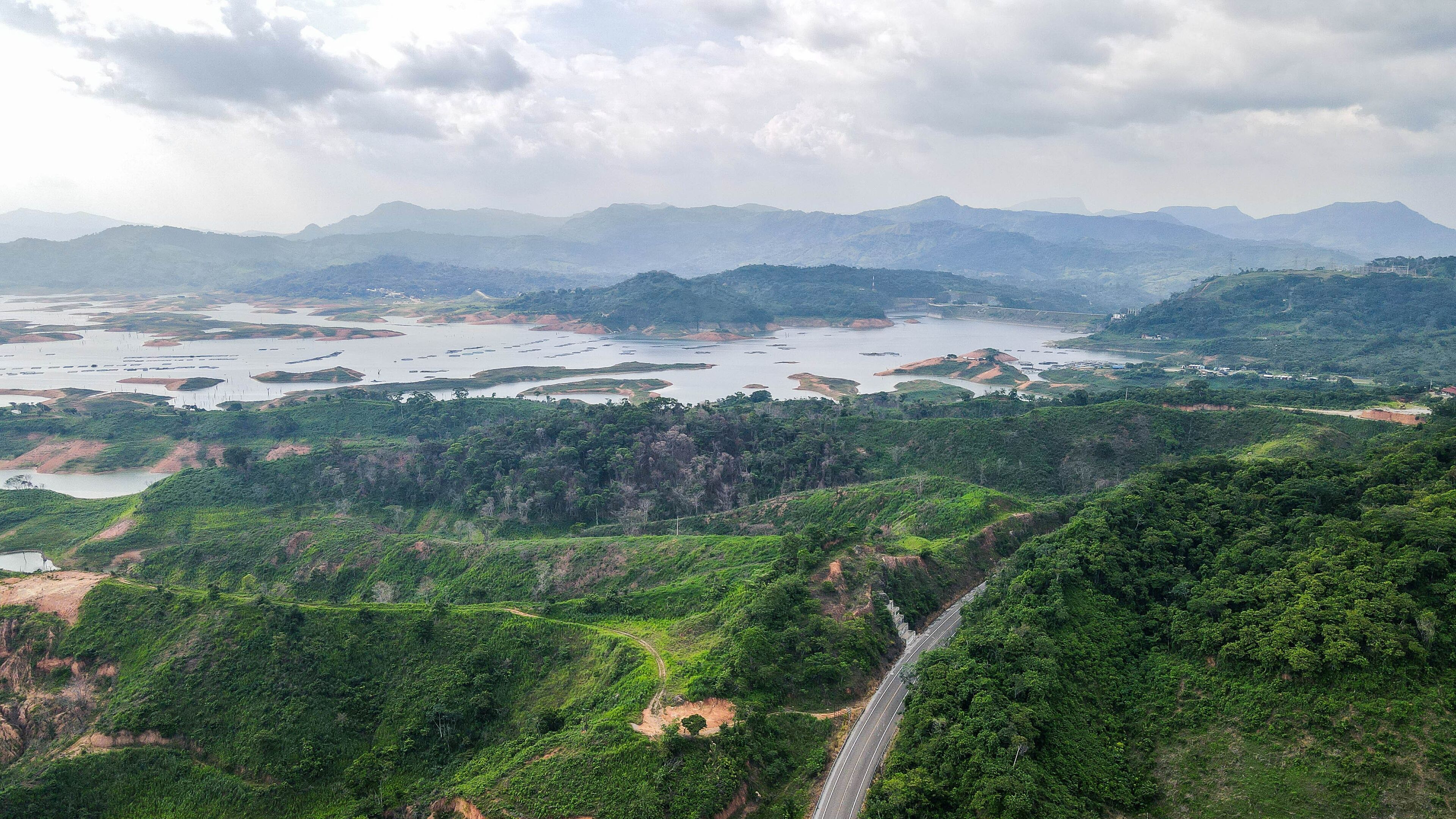 A river with multiple islands, surrounded by lush green hills and mountains in the background.