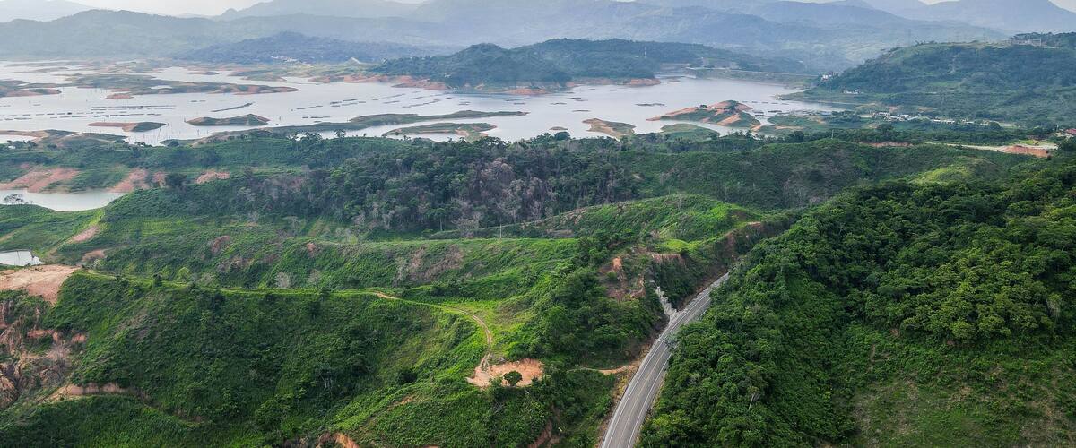 A river with multiple islands, surrounded by lush green hills and mountains in the background.
